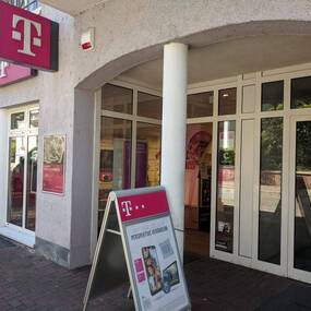 Eingang eines Telekom Shops mit Werbeaufsteller und Glasfassade in einer Innenstadt.