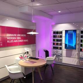 Modernes Telekommunikationsgeschäft mit Beratungstisch, Wanddisplay und Smartphone-Zubehör.