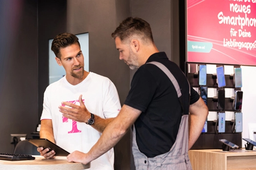Beratung im Handyshop: Verkäufer zeigt Smartphone-Angebot am Tablet